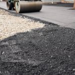 Closeup new hot asphalt. Laying asphalt, covering the pit, on the rubble. Asphalt Compactors is carrying out road repair work